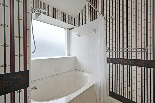 bathroom with a textured ceiling and shower / bath combination with curtain