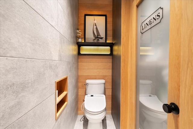 bathroom with toilet, built in features, and wood walls