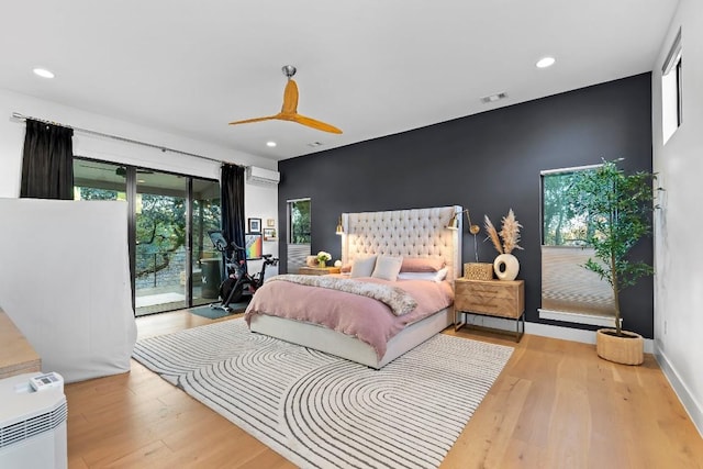 bedroom with access to exterior, a wall mounted air conditioner, ceiling fan, and light wood-type flooring