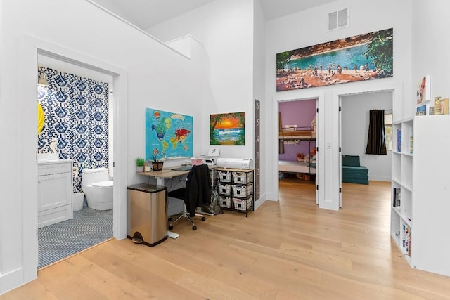 office with a towering ceiling and light hardwood / wood-style flooring