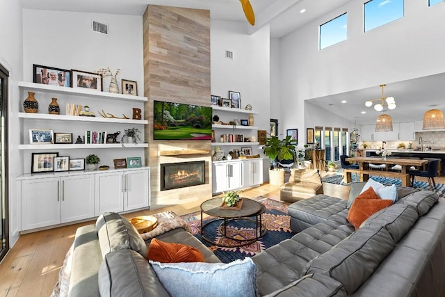 living room with a tile fireplace, a chandelier, and light wood-type flooring