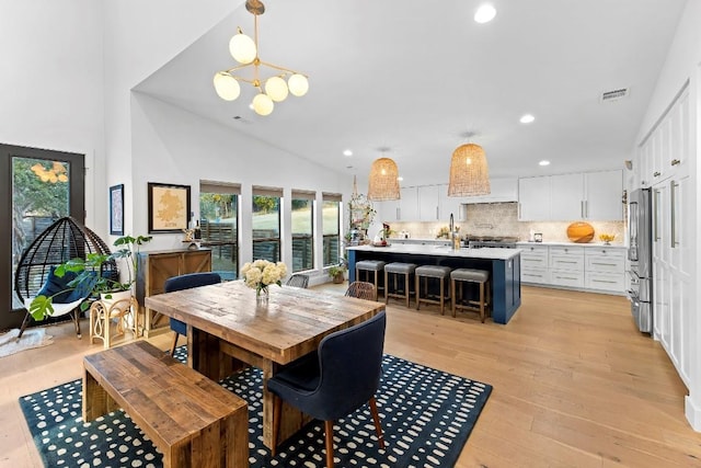 dining room with an inviting chandelier, lofted ceiling, and light wood-type flooring