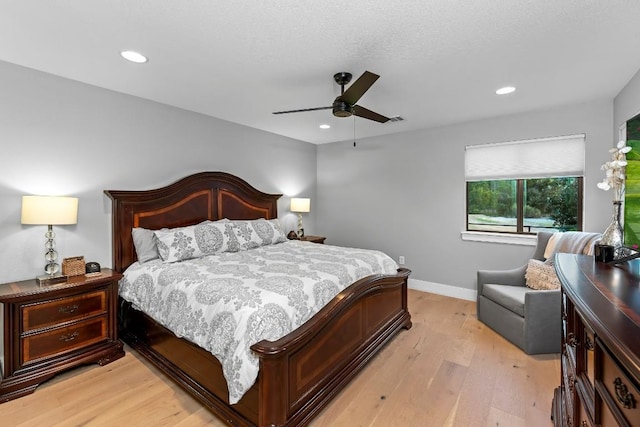 bedroom featuring ceiling fan, light hardwood / wood-style floors, and a textured ceiling