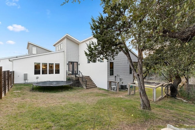 back of property with a yard and a trampoline