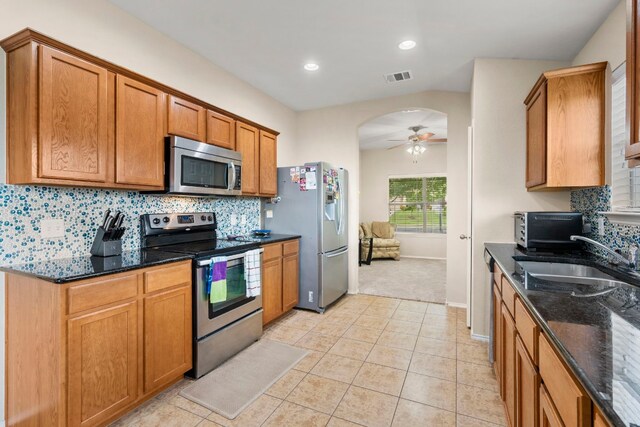 kitchen with tasteful backsplash, ceiling fan, dark stone countertops, sink, and appliances with stainless steel finishes