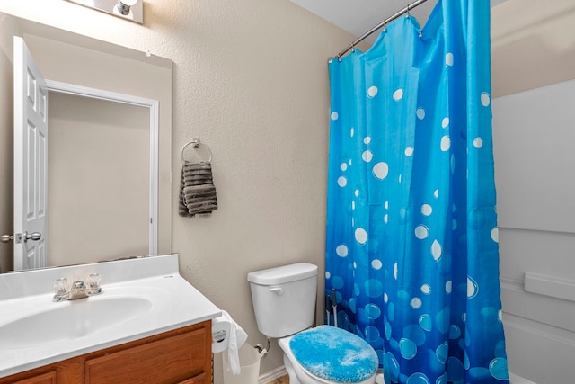 bathroom featuring toilet, walk in shower, and vanity