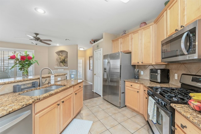 kitchen with sink, light brown cabinets, light tile patterned floors, and stainless steel appliances