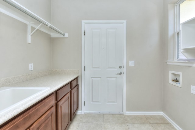 washroom with washer hookup, light tile patterned floors, and sink