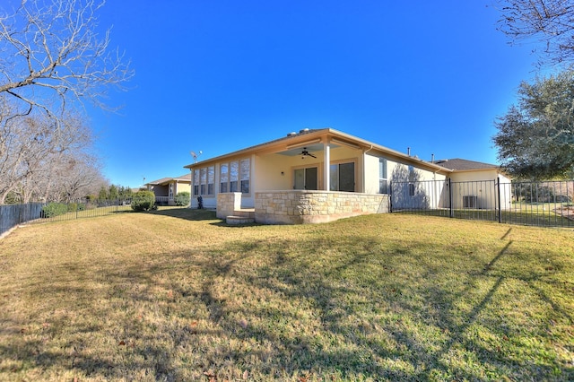 back of house with ceiling fan and a yard