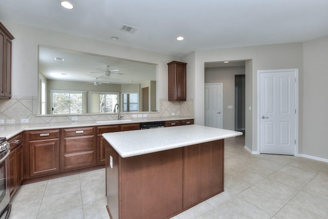 kitchen with a kitchen island, stainless steel appliances, tasteful backsplash, sink, and light tile patterned floors