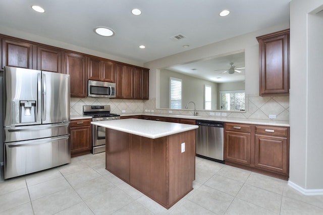 kitchen with ceiling fan, stainless steel appliances, backsplash, light tile patterned flooring, and a center island