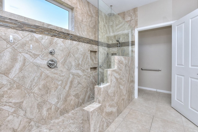 bathroom with a tile shower and tile patterned flooring