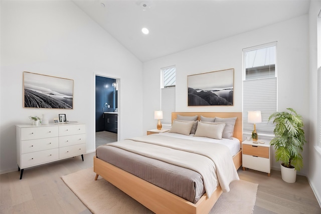 bedroom with light wood-type flooring, connected bathroom, and high vaulted ceiling