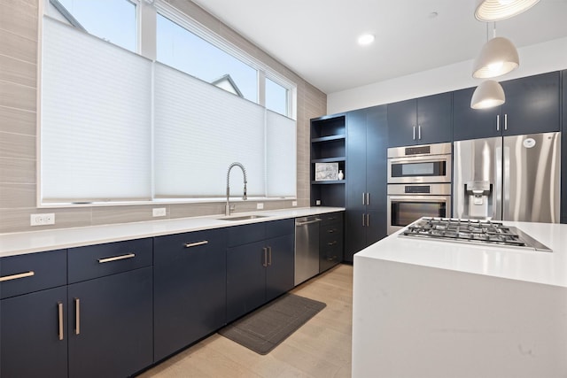 kitchen with stainless steel appliances, blue cabinets, hanging light fixtures, and sink