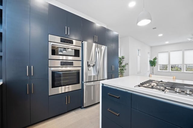 3100 Menchaca Rd Unit 29, Austin, TX 78704 - kitchen with appliances with stainless steel finishes, blue cabinetry, light countertops, light wood-style floors, and decorative light fixtures