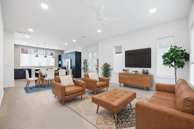 living room with light wood-type flooring and ceiling fan