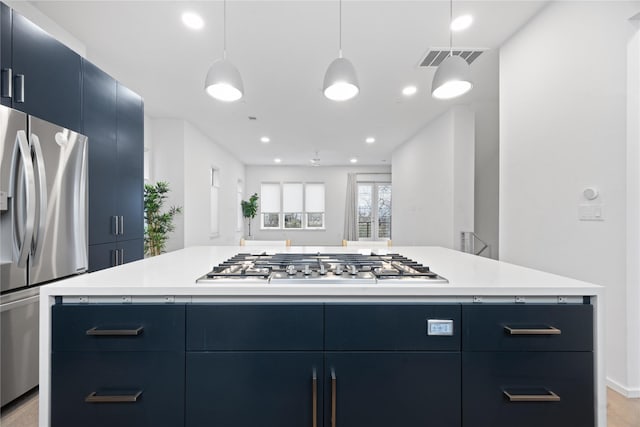 kitchen with hanging light fixtures, appliances with stainless steel finishes, a center island, and blue cabinets