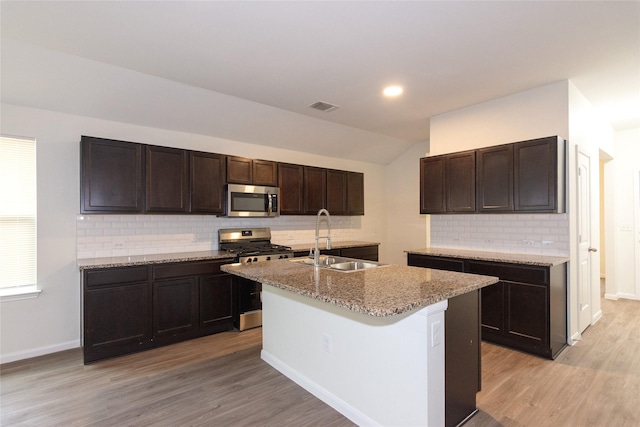 kitchen with a center island with sink, sink, light hardwood / wood-style flooring, dark brown cabinetry, and stainless steel appliances