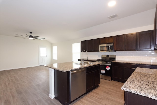 kitchen featuring ceiling fan, decorative backsplash, sink, an island with sink, and stainless steel appliances