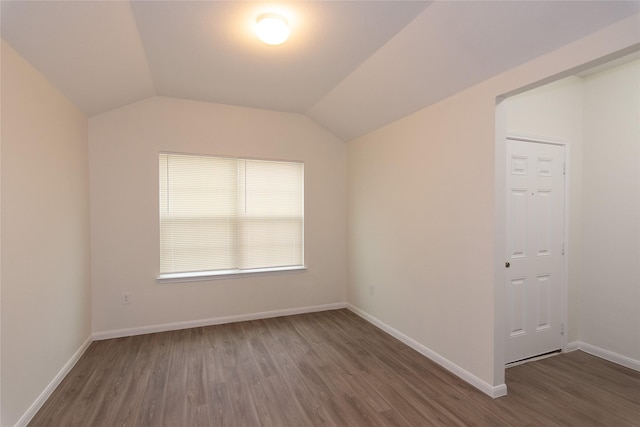 spare room featuring vaulted ceiling and dark hardwood / wood-style flooring