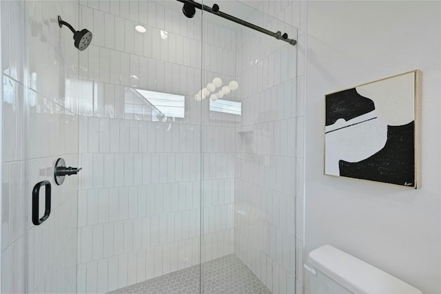 bathroom with a shower with shower door and toilet