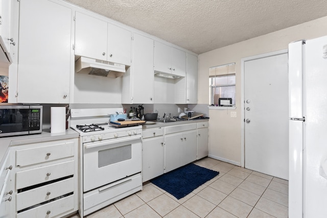 kitchen featuring a textured ceiling, light tile patterned floors, white cabinets, and white appliances