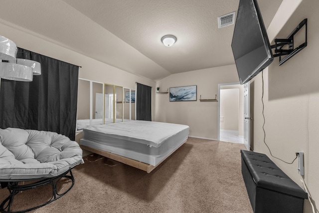 bedroom featuring vaulted ceiling, carpet flooring, and a textured ceiling