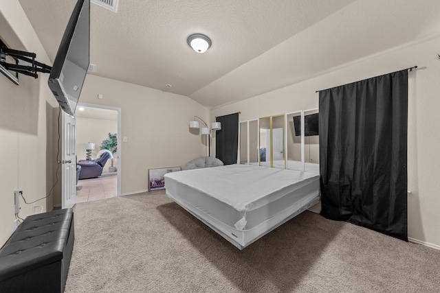 bedroom with light carpet, vaulted ceiling, and a textured ceiling