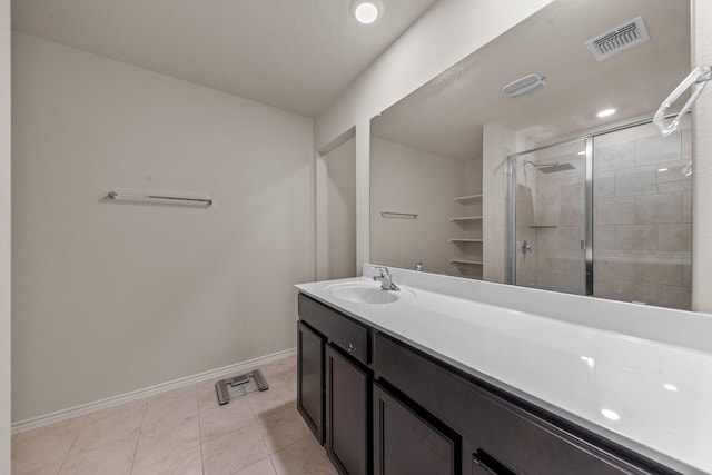 bathroom with a shower with shower door, vanity, and tile patterned flooring