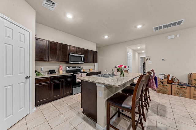 kitchen featuring appliances with stainless steel finishes, sink, a kitchen island with sink, light tile patterned floors, and a breakfast bar area