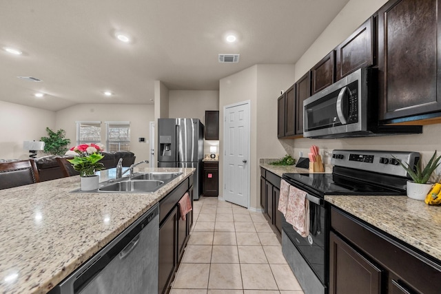 kitchen featuring lofted ceiling, stainless steel appliances, sink, light tile patterned flooring, and light stone counters