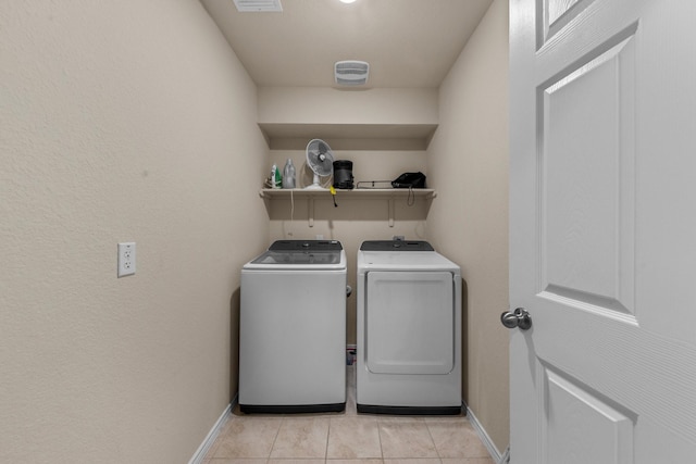 laundry area with light tile patterned floors and washing machine and clothes dryer