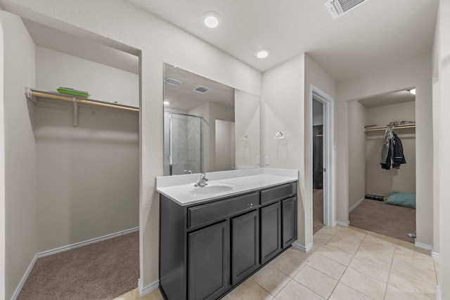 bathroom with a shower with shower door, vanity, and tile patterned flooring