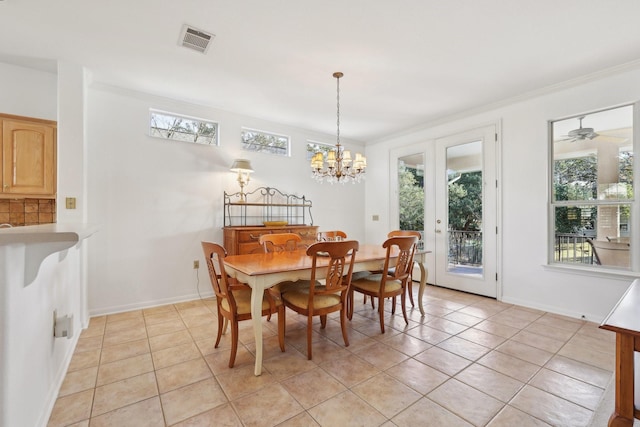 dining room with ceiling fan with notable chandelier, ornamental molding, french doors, and light tile patterned flooring