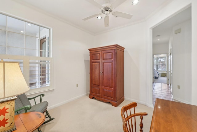 sitting room featuring ceiling fan, ornamental molding, and light carpet