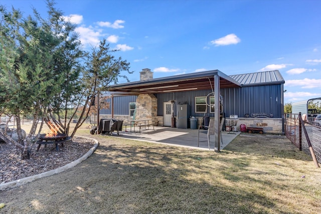 back of house featuring a lawn, a fire pit, and a patio