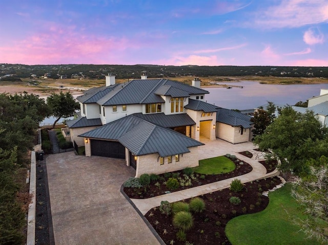 aerial view at dusk featuring a water view