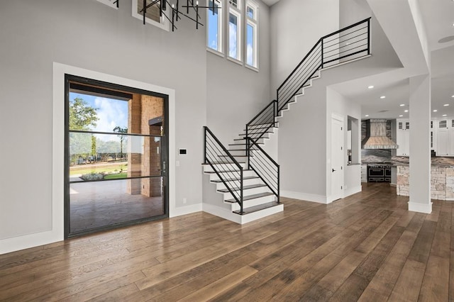 foyer entrance with dark wood-type flooring, a wealth of natural light, and a towering ceiling