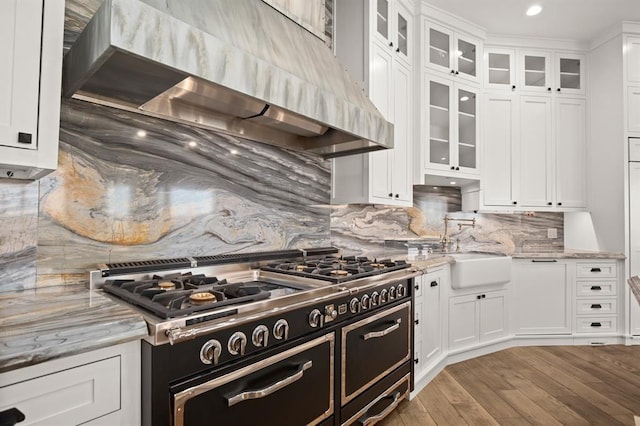 kitchen featuring white cabinetry, light stone counters, and wall chimney range hood