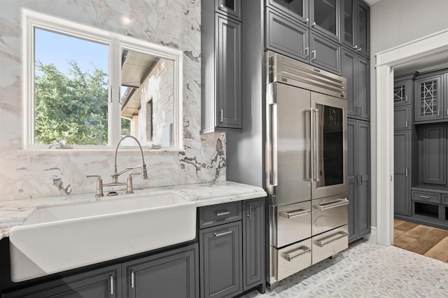 kitchen with light stone countertops, sink, and built in fridge