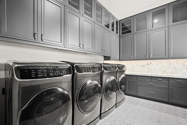 clothes washing area with cabinets and washer and dryer