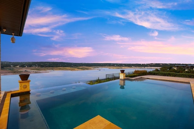 pool at dusk featuring a water view