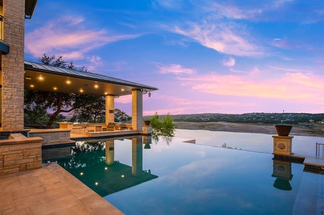 pool at dusk featuring a water view