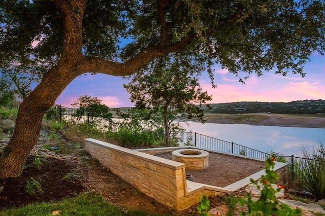 yard at dusk with an outdoor fire pit and a water view