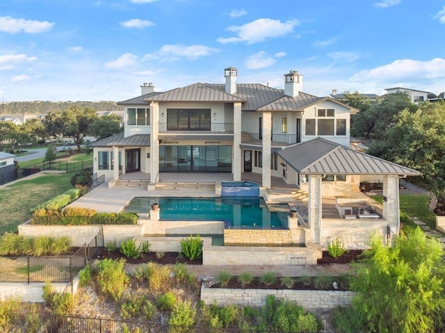 rear view of house featuring a swimming pool with hot tub, a gazebo, and a patio