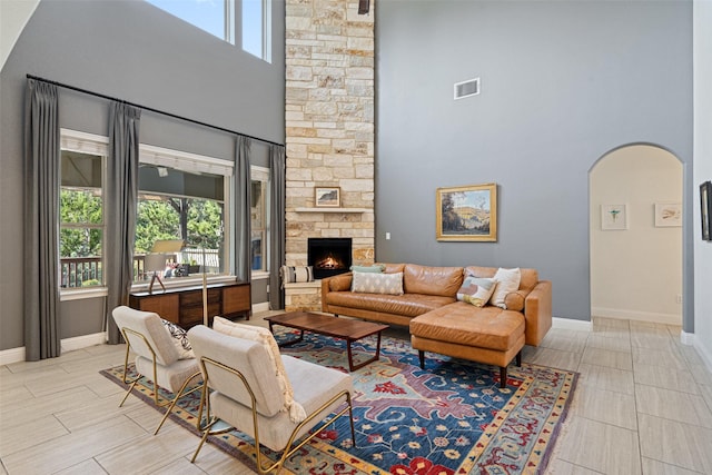 living room featuring a fireplace, a wealth of natural light, and a towering ceiling