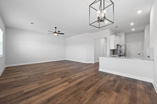 unfurnished living room featuring dark wood-type flooring and ceiling fan with notable chandelier