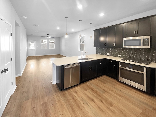 kitchen featuring appliances with stainless steel finishes, sink, hanging light fixtures, kitchen peninsula, and ceiling fan