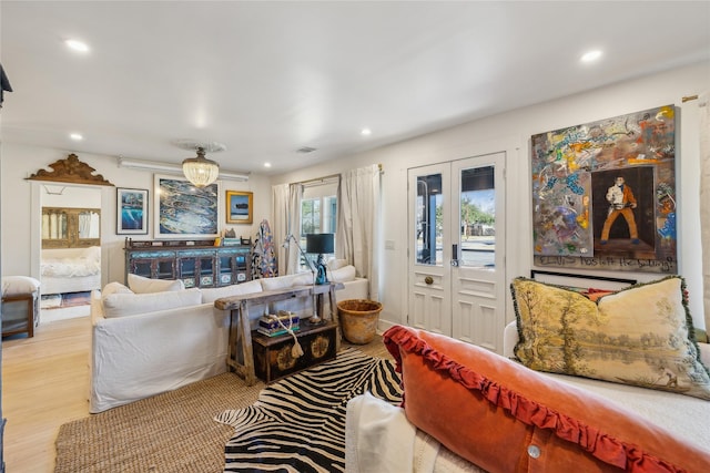 living room featuring light wood-type flooring, french doors, and an inviting chandelier