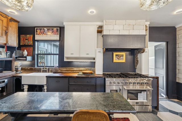 kitchen featuring dark stone countertops, gray cabinets, sink, white cabinetry, and range with two ovens